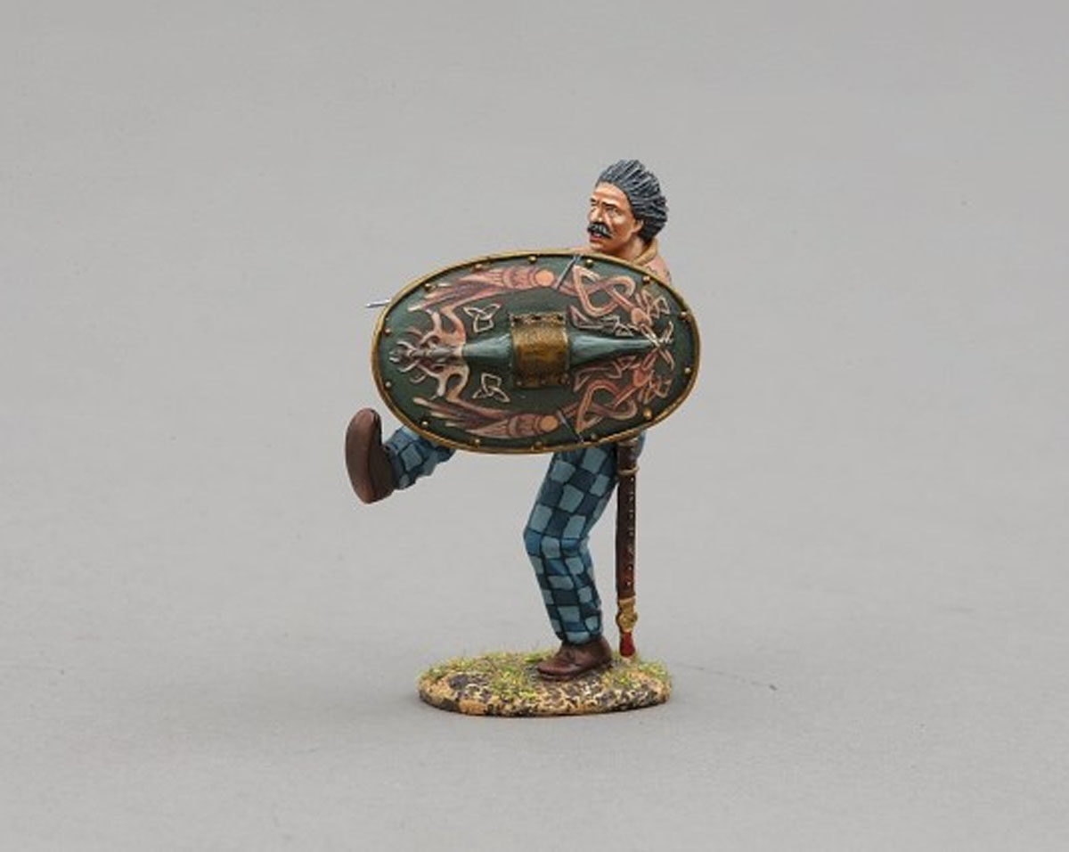 Ancient Briton adorned with tattoos holding ornate green shield decorated with mythical waterbirds