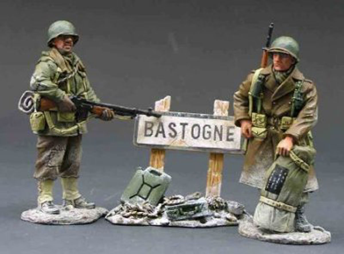 Soldati che si riposano davanti al cartello per Bastogne